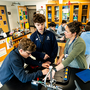 A teacher helping students with a science project. Links to Gifts That Pay You Income